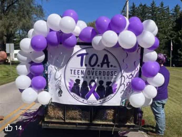 T.O.A. community parade display with purple and white balloons